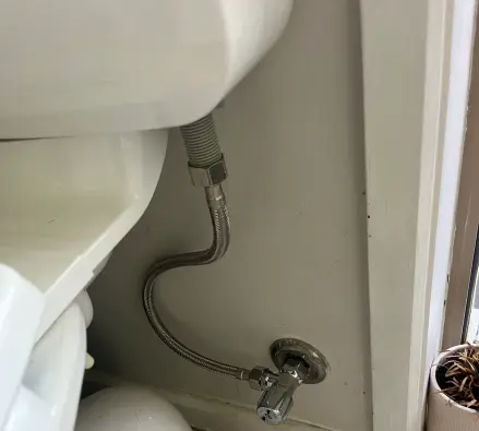 Braided flexible hose and chrome angle stop supplying a toilet cistern