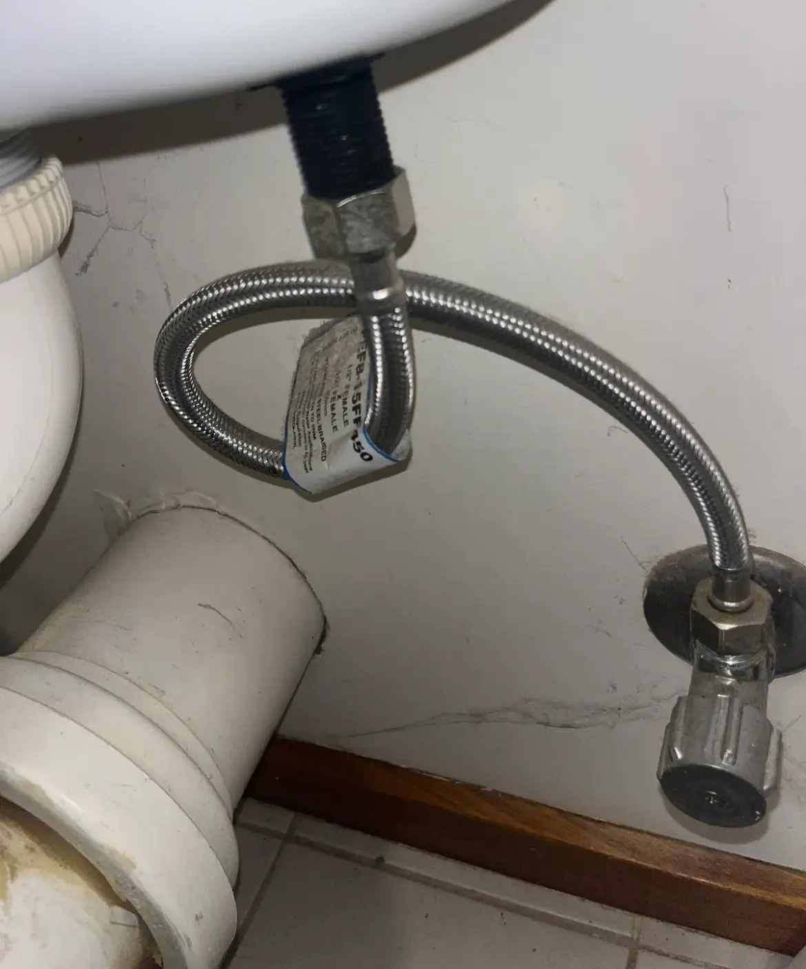 Braided flexible hose connected to an angle stop under a basin