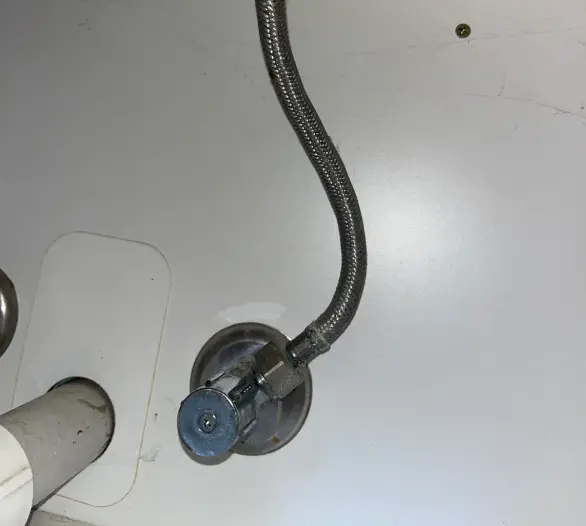 Braided flexible hose connected to an angle stop under a basin