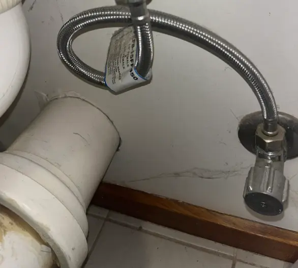 Braided flexible hose connected to an angle stop under a basin