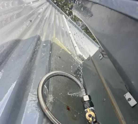 Braided hose with water spraying from a fitting on a tank or roof