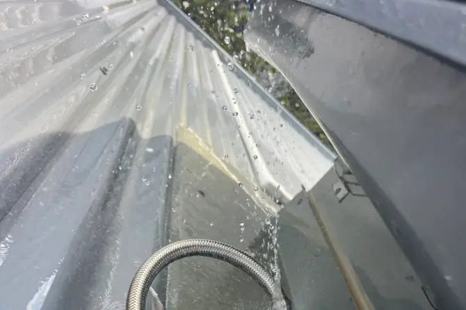 Braided hose with water spraying from a fitting on a tank or roof