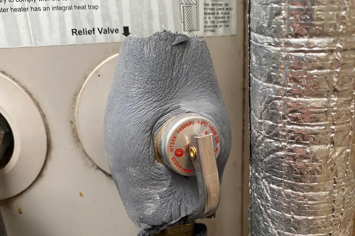 Close-up of an insulated temperature and pressure relief valve on a hot water unit