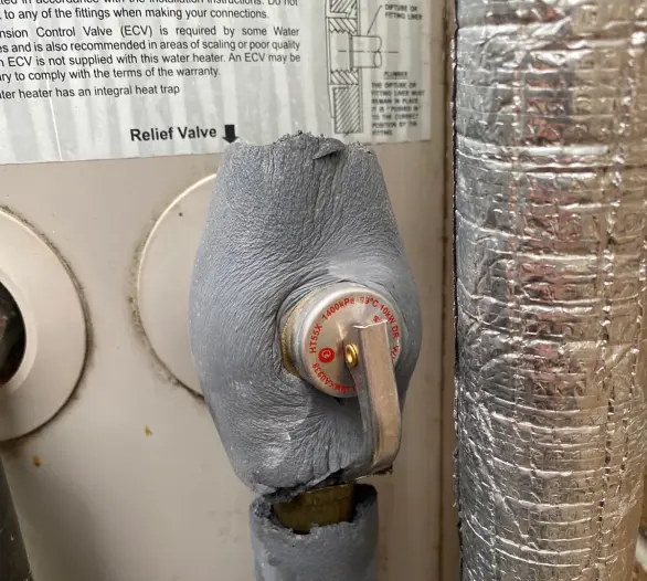Close-up of an insulated temperature and pressure relief valve on a hot water unit