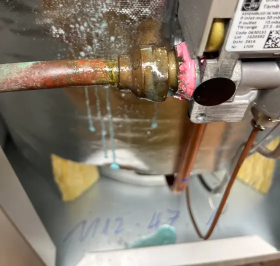 Close view of a hot water valve with water droplets beneath it