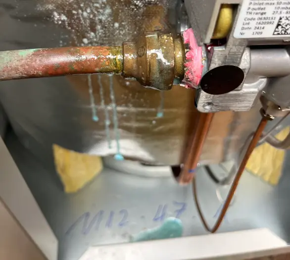 Close view of a hot water valve with water droplets beneath it