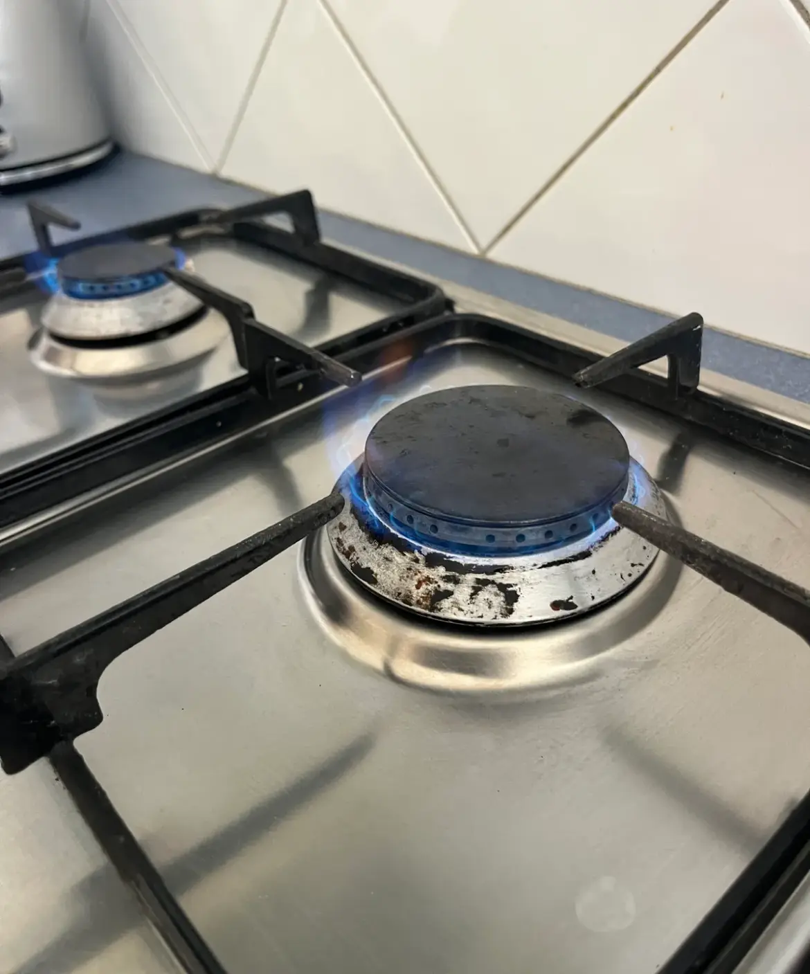 Close view of a lit gas burner on a cooktop with a blue flame