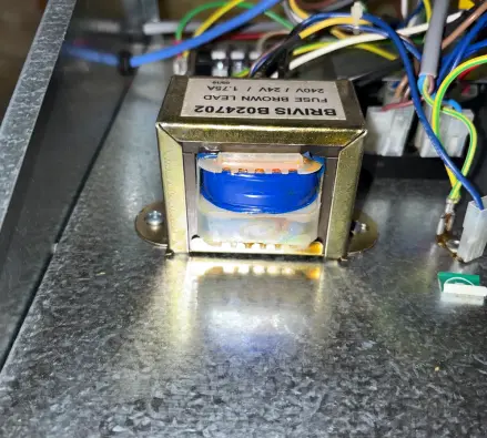 Close view of a small transformer with a rating label inside a heater