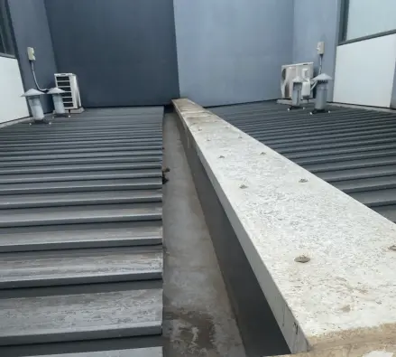 Concrete-capped box gutter between metal roof sections