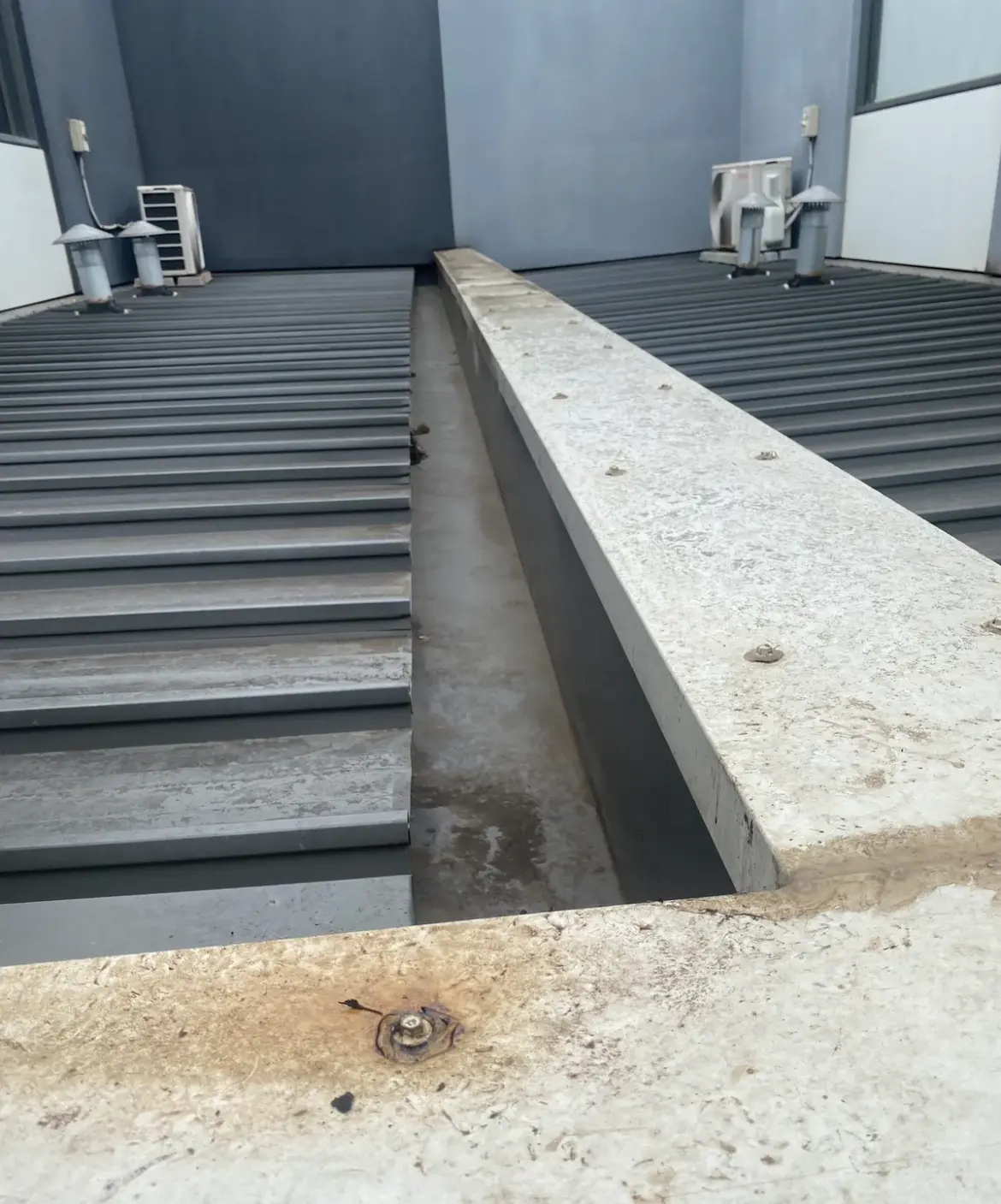 Concrete-capped box gutter between metal roof sections