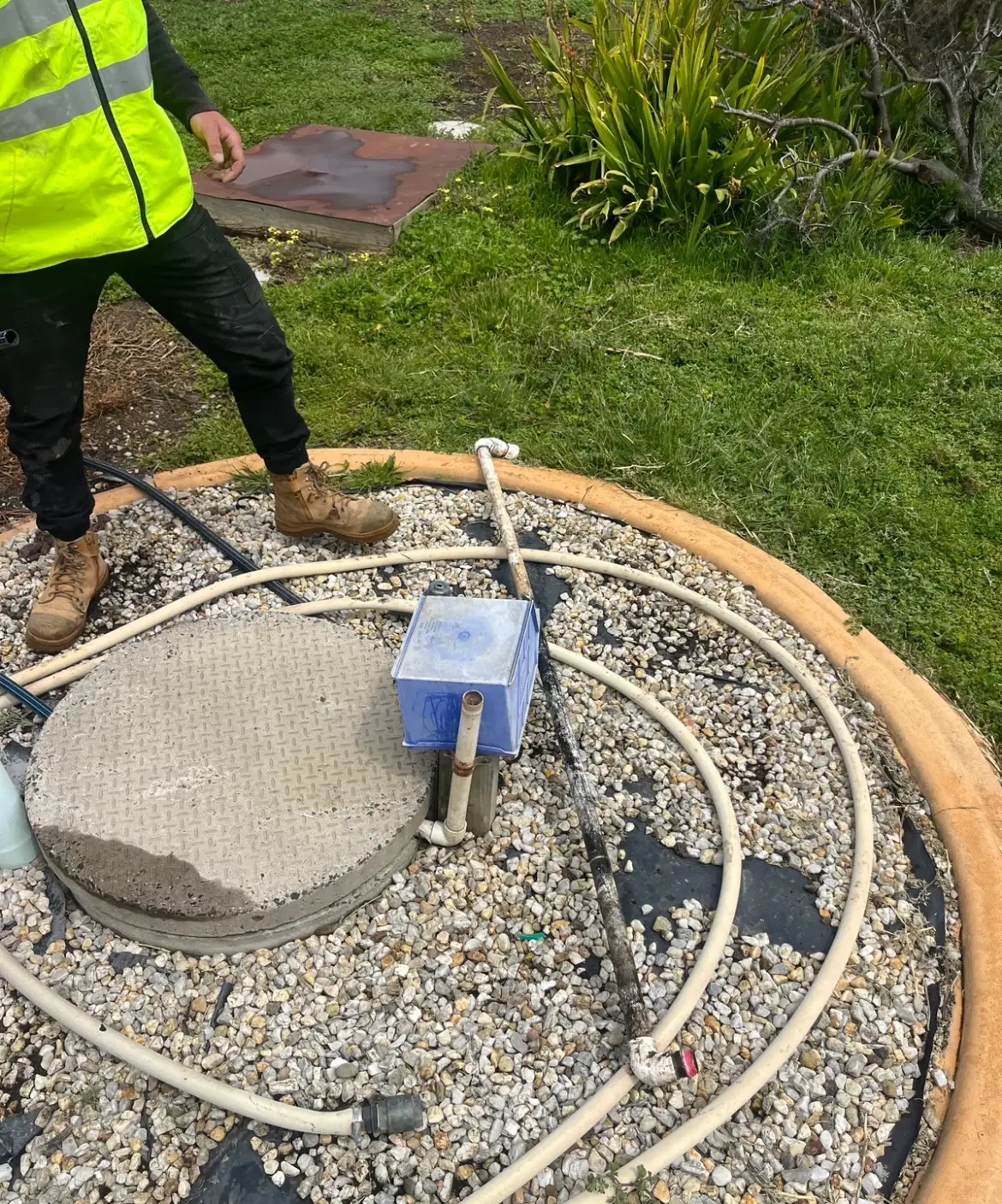 Concrete pit lid, pump box and hose coils on a gravel pad