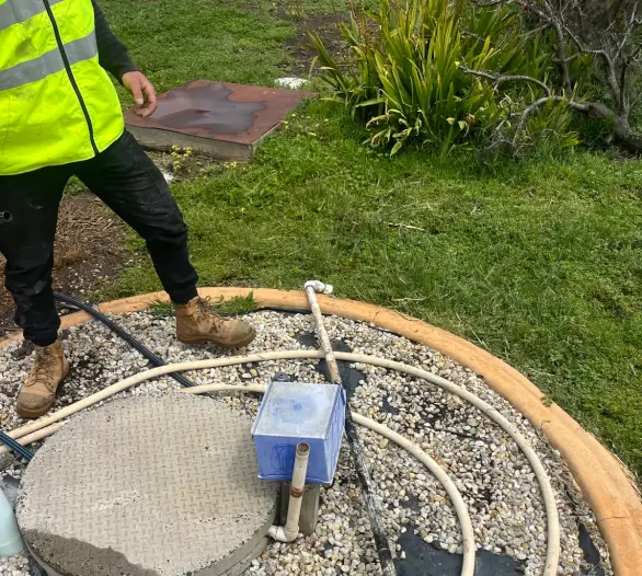 Concrete pit lid, pump box and hose coils on a gravel pad