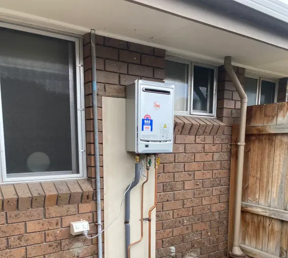 Continuous flow hot water unit on a brick wall with tidy copper pipework