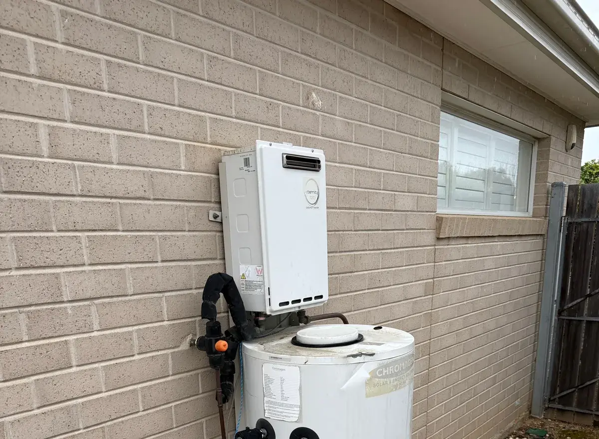 Continuous flow unit mounted on a white storage tank beside a pale brick wall and gravel