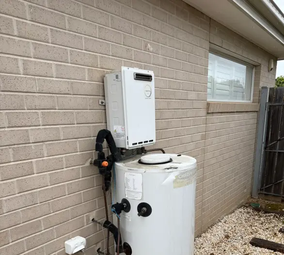 Continuous flow unit mounted on a white storage tank beside a pale brick wall and gravel