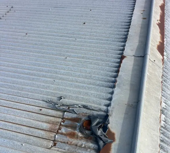 Damaged flashing at a roof penetration with a work boot at the edge