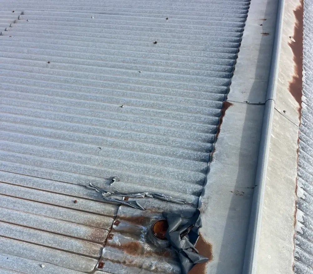 Damaged flashing at a roof penetration with a work boot at the edge