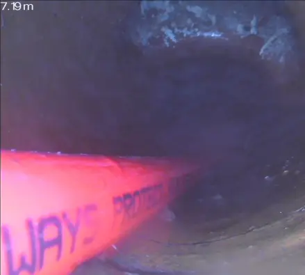 Drain camera view inside a pipe showing the camera cable and a distance reading