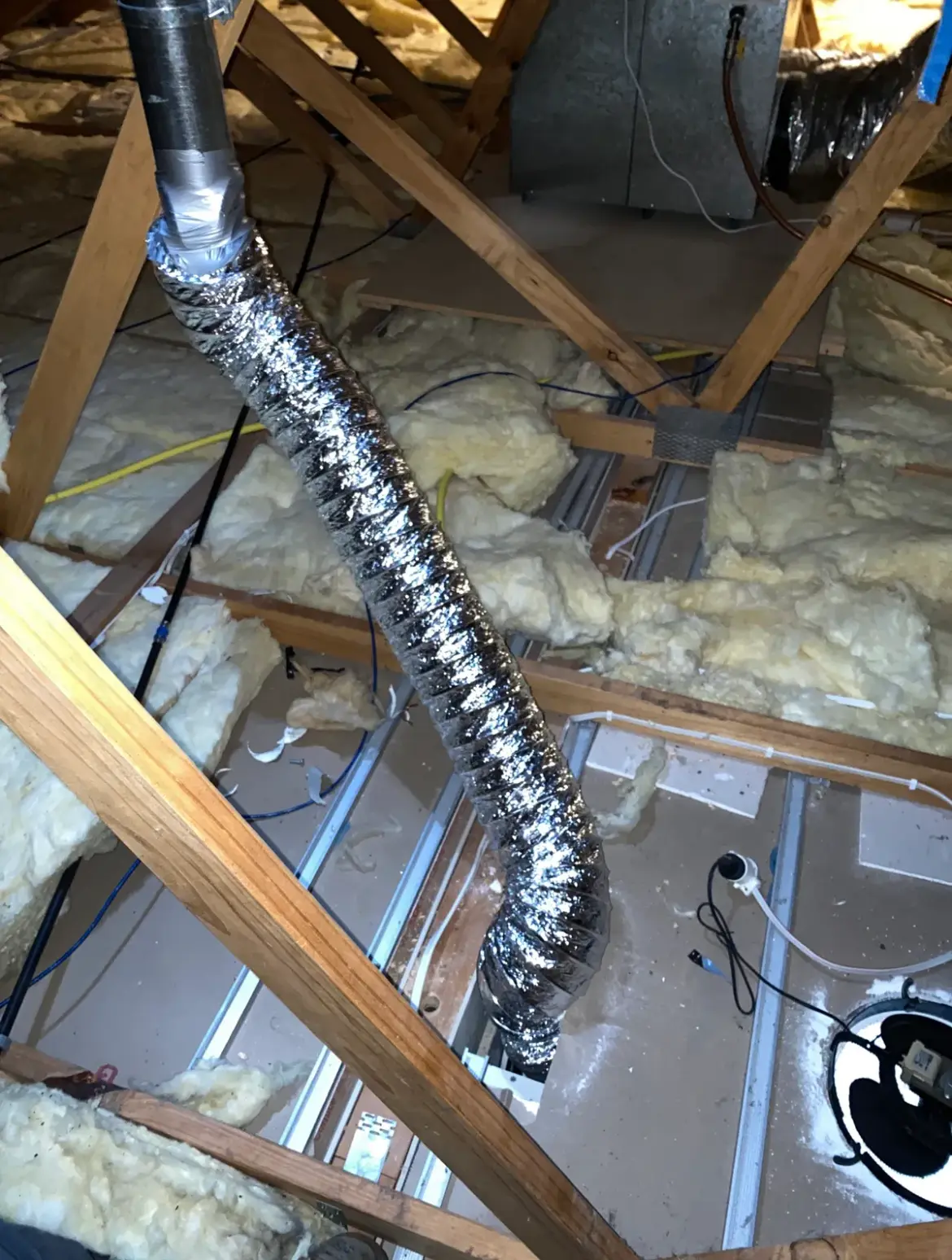 Ducting and a flue pipe through insulation in a roof space