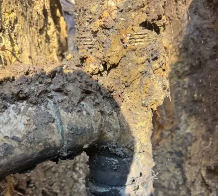 Excavated underground drain pipe and a PVC connection in a trench