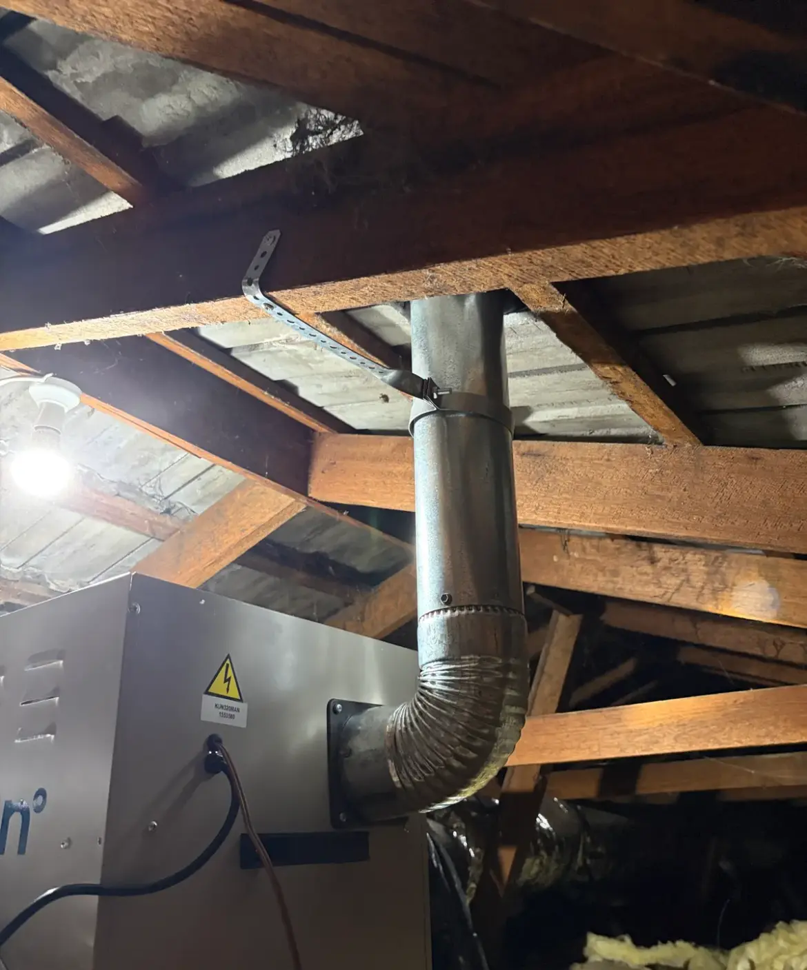 Fan unit and flue pipes in a roof space