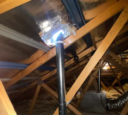Flue and flexible ducting surrounded by roof-space insulation