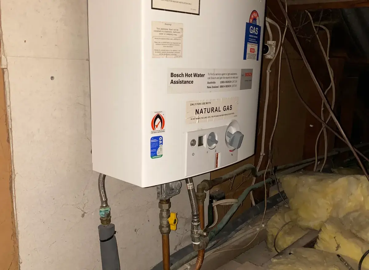 Gas hot water unit installed in a roof space with warning labels