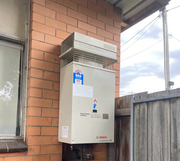 Gas hot water unit mounted on an outside wall with copper pipework