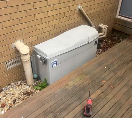 Gas hot water unit tucked under a timber deck with a power drill beside it