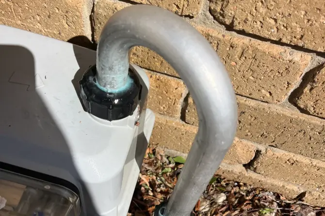 Gas meter and galvanised pipe on a brick wall above garden mulch
