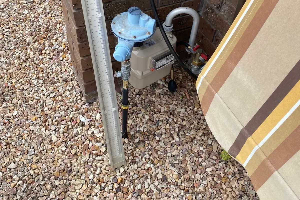 Gas pressure manometer attached at a meter beside a brick wall