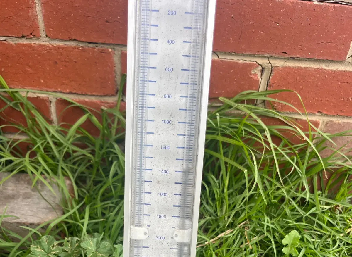 Gas pressure manometer standing in grass against a red brick wall