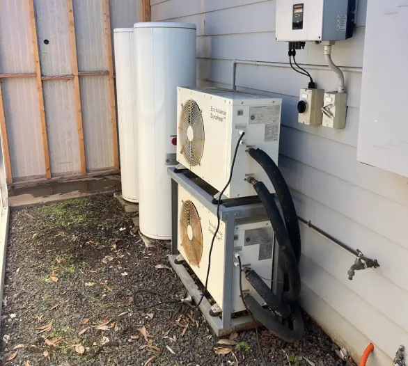 Heat pump units and storage cylinders against an outside wall