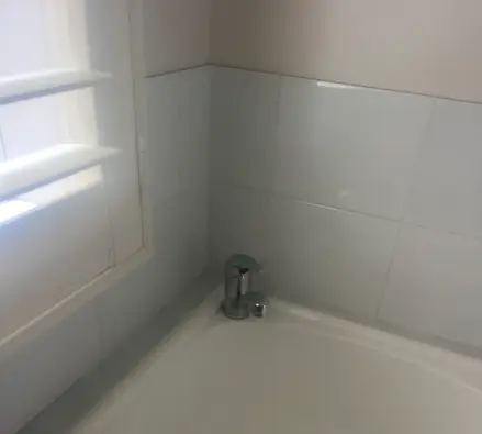 Laundry tub with a small chrome mixer tap beside a louvre window