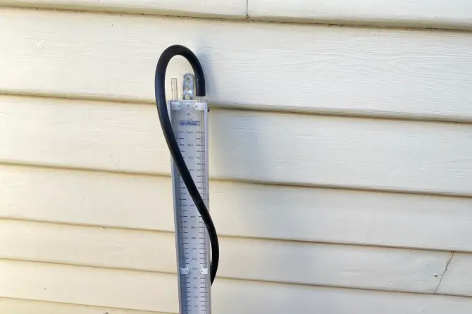 Manometer test gauge connected to a gas meter above tidy gravel