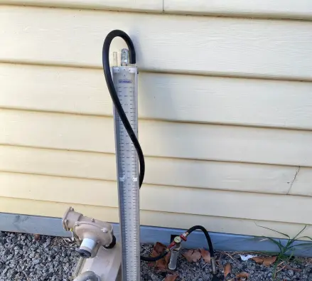 Manometer test gauge connected to a gas meter above tidy gravel