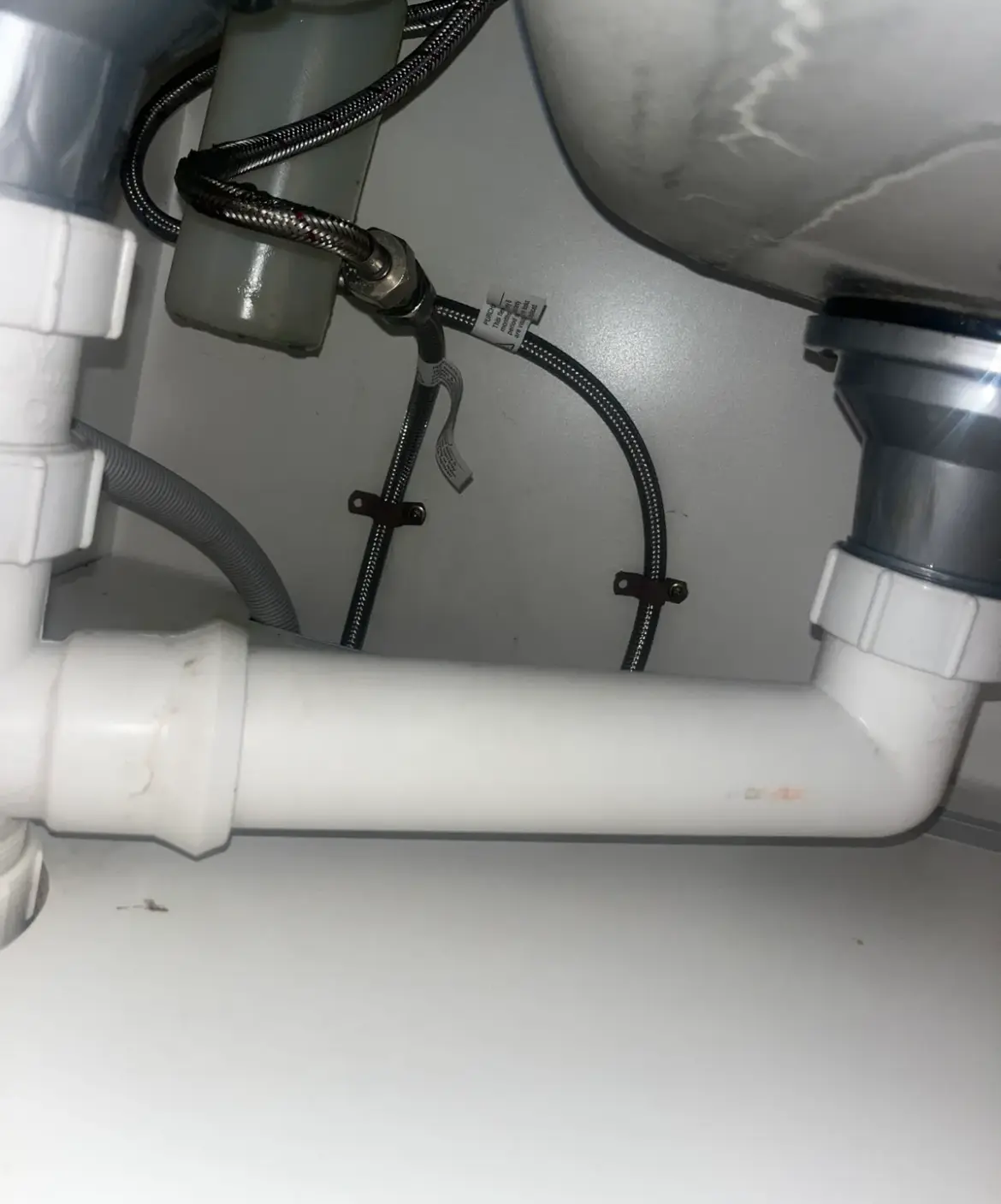 Pipework and traps under a sink in a cupboard