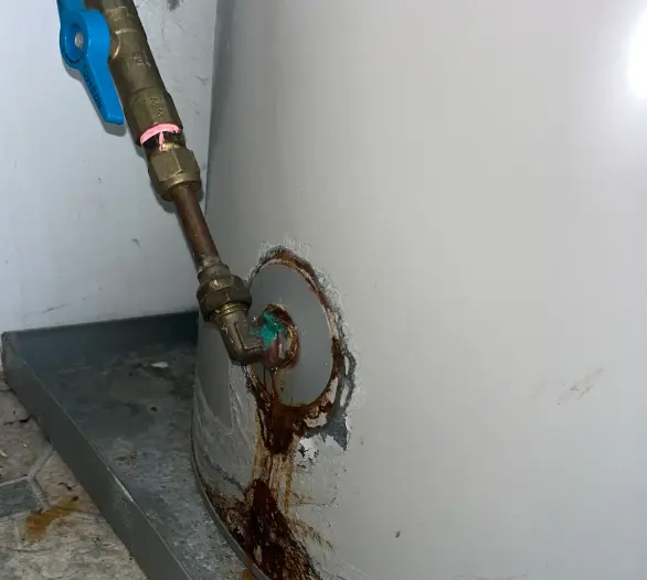 Rust streaks around the pipe connection at the base of a hot water cylinder