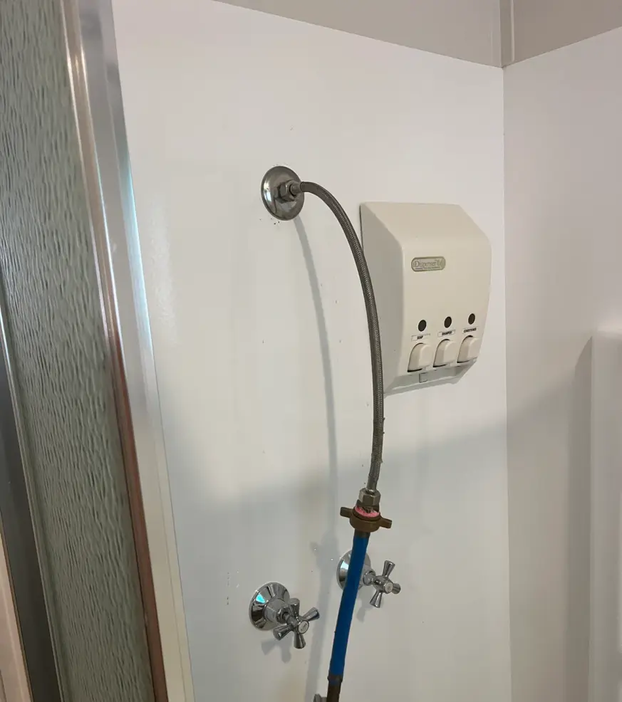 Shower recess with a pressure test hose connected to the outlet