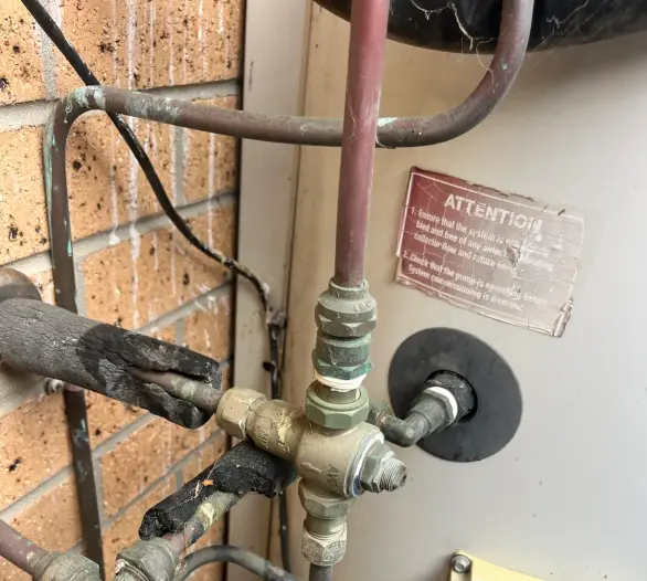 Tempering valve and pipework on a solar hot water system with a warning sticker