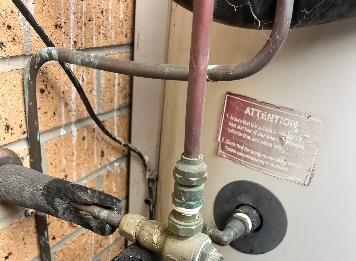Tempering valve and pipework on a solar hot water system with a warning sticker