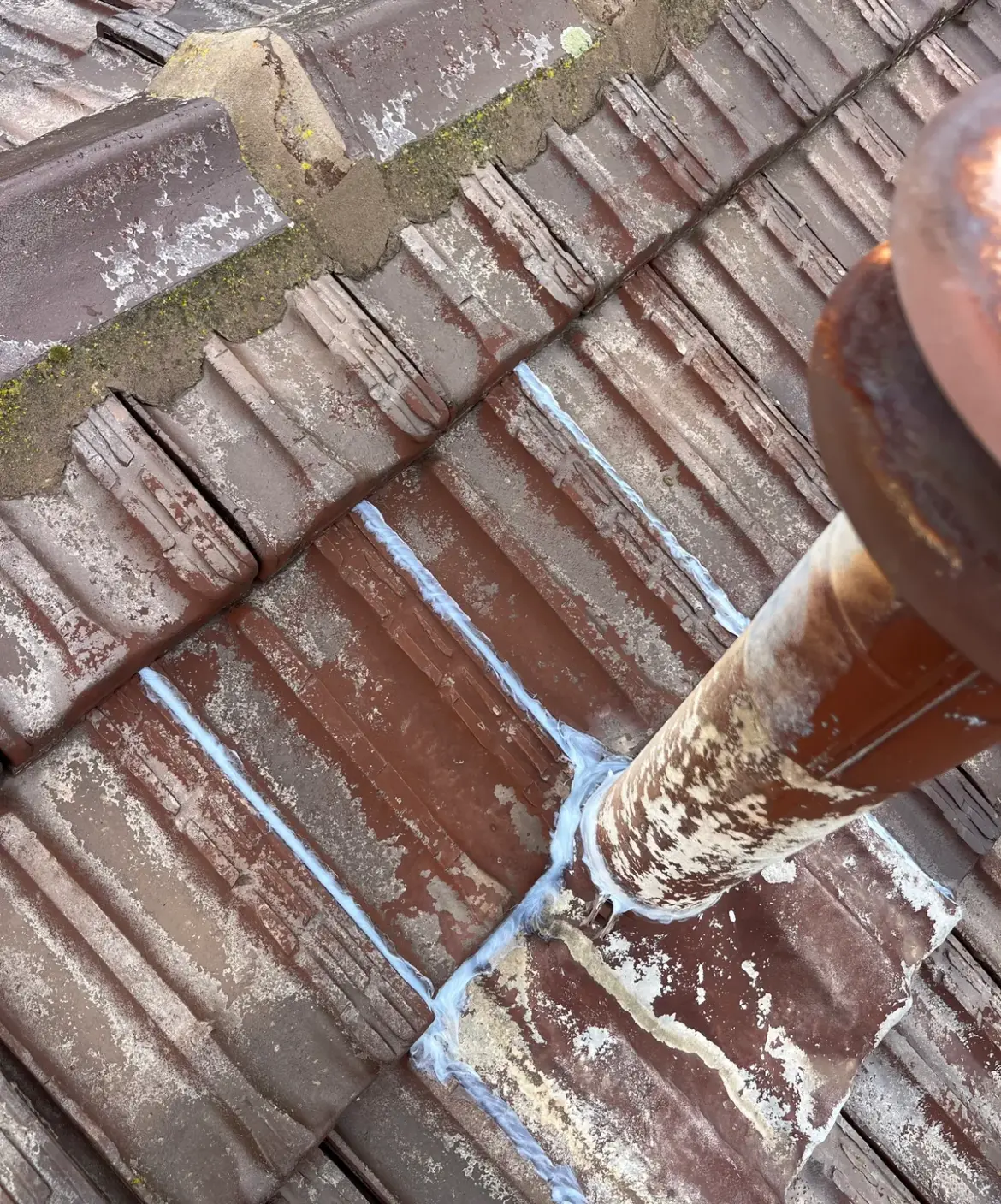 Tiled roof with fresh sealant lines around a pipe penetration