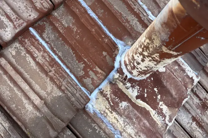 Tiled roof with fresh sealant lines around a pipe penetration