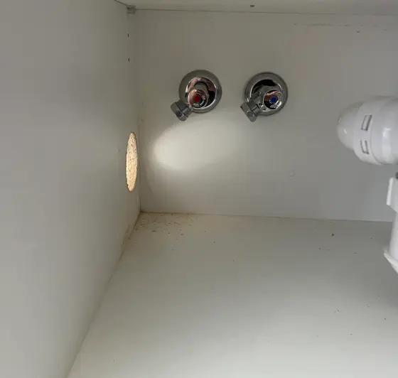 Two chrome angle stops marked red and blue inside an empty cabinet