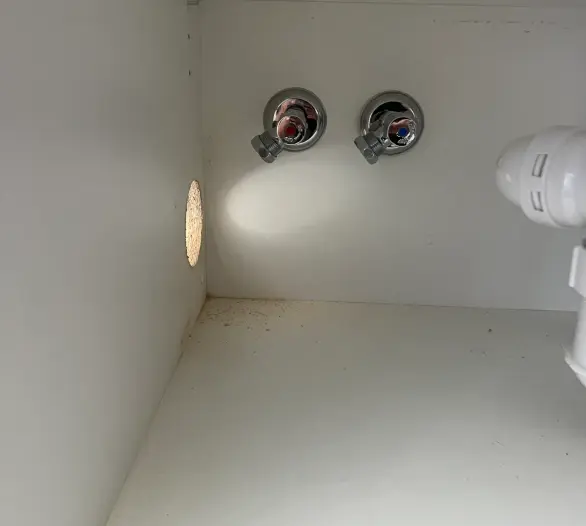 Two chrome angle stops marked red and blue inside an empty cabinet