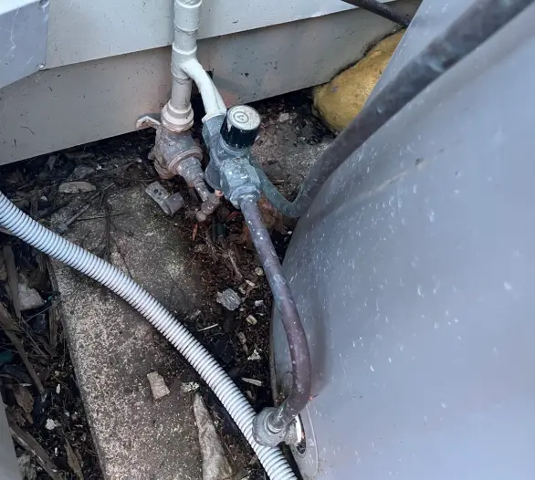 Valves and copper pipework between a weatherboard wall and a hot water unit
