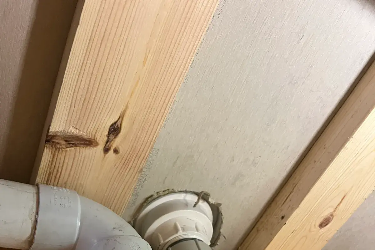 White PVC trap and waste pipe fitted on timber framing under plasterboard