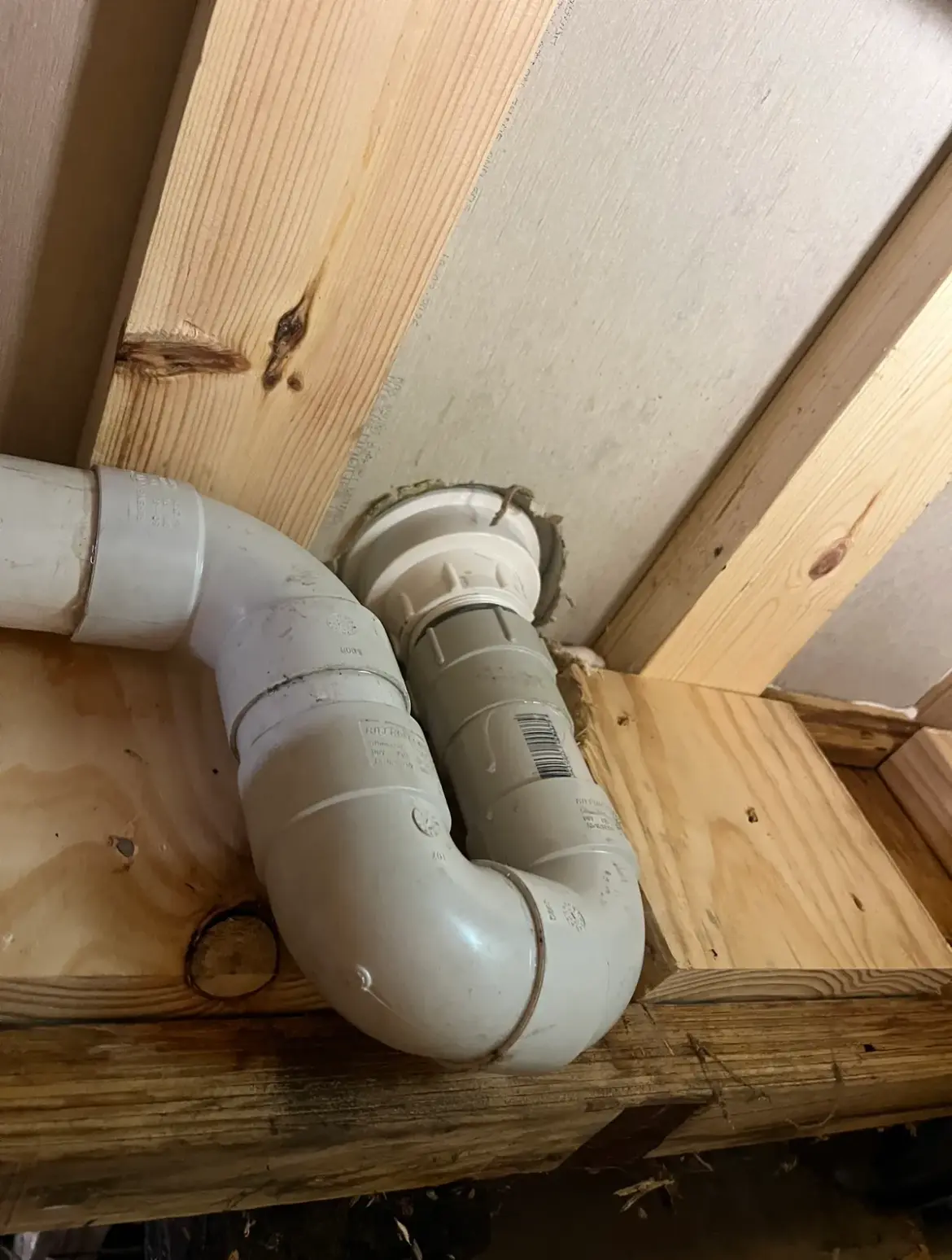 White PVC trap and waste pipe fitted on timber framing under plasterboard